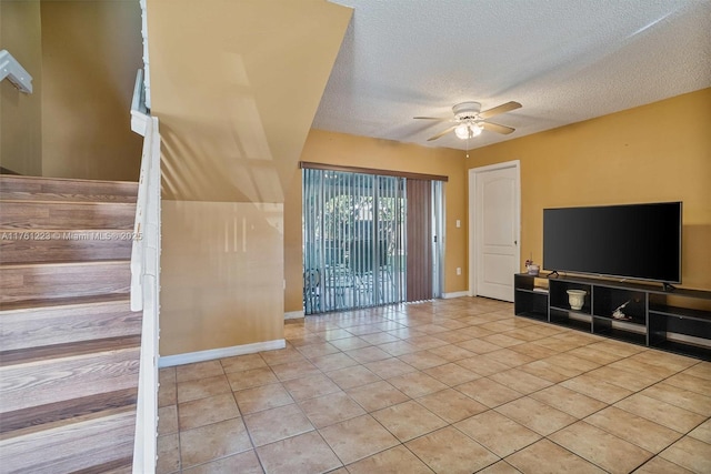 unfurnished living room featuring a textured ceiling, stairs, a ceiling fan, baseboards, and light tile patterned floors