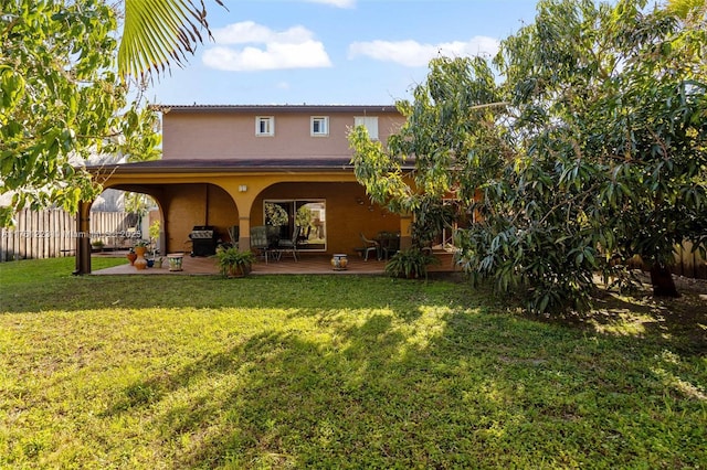 rear view of property with a yard, a deck, fence, and stucco siding