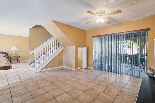 tiled spare room featuring baseboards, stairway, a textured ceiling, and a ceiling fan