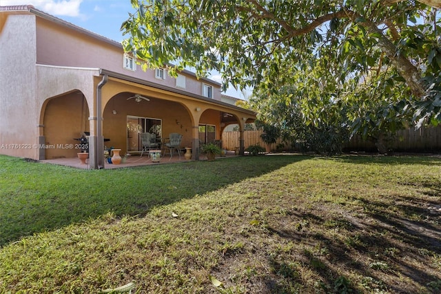 rear view of house with a patio, a ceiling fan, fence, stucco siding, and a lawn