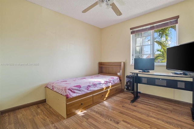 bedroom featuring a textured ceiling, a ceiling fan, baseboards, and wood finished floors