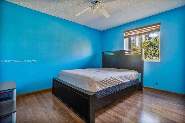 bedroom featuring ceiling fan, a textured ceiling, baseboards, and wood finished floors
