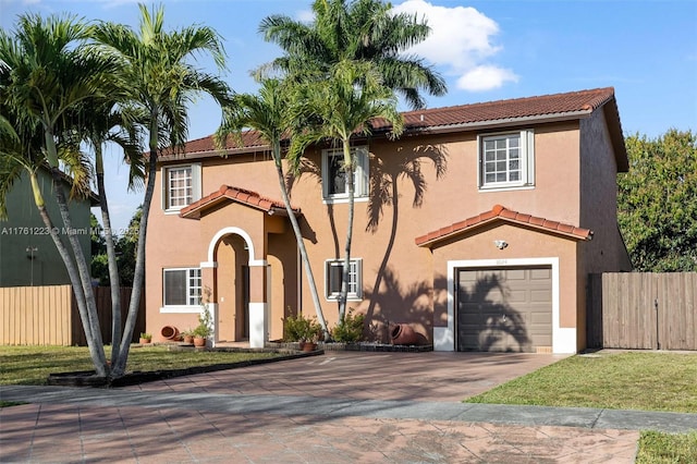 mediterranean / spanish house with fence, a tiled roof, driveway, and a garage
