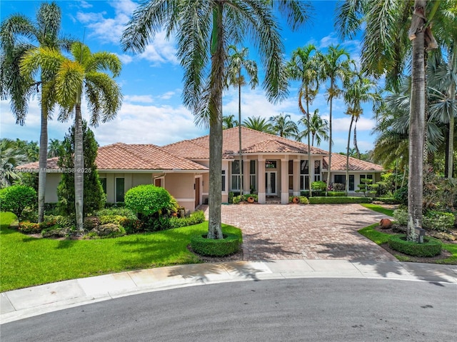 mediterranean / spanish-style home featuring a front lawn, a tiled roof, decorative driveway, and stucco siding