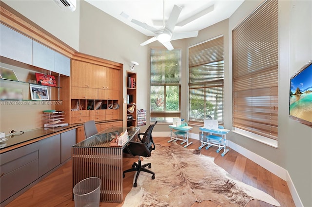 office featuring baseboards, wood finished floors, and a wall mounted AC