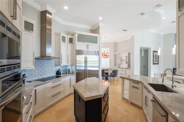 kitchen featuring built in appliances, ornamental molding, decorative backsplash, wall chimney exhaust hood, and a sink