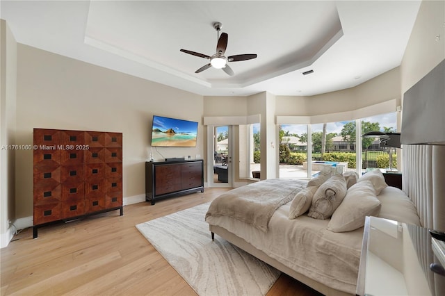 bedroom with visible vents, a tray ceiling, ceiling fan, access to outside, and light wood-type flooring