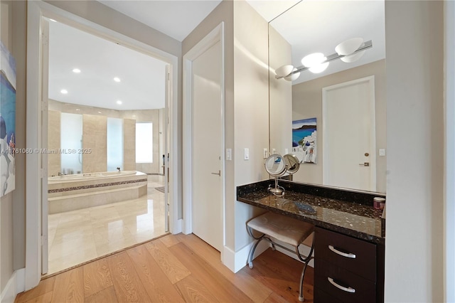 full bath featuring vanity, a garden tub, recessed lighting, and wood finished floors