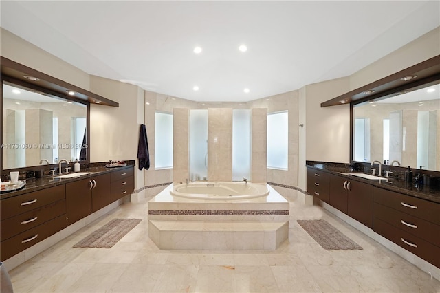 bathroom featuring a sink, a jetted tub, and two vanities