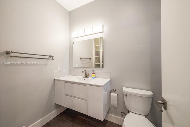 half bathroom with baseboards, toilet, wood finished floors, and vanity