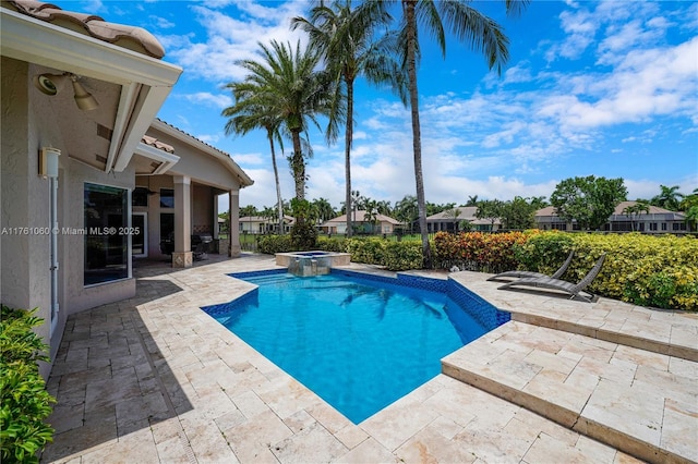 view of pool featuring a patio, fence, and a pool with connected hot tub