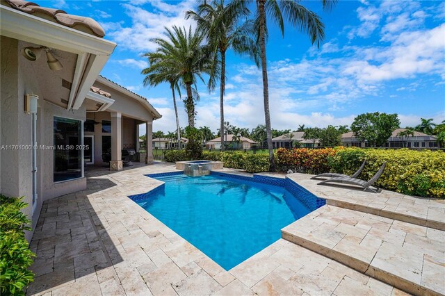 view of pool featuring a patio, fence, and a pool with connected hot tub