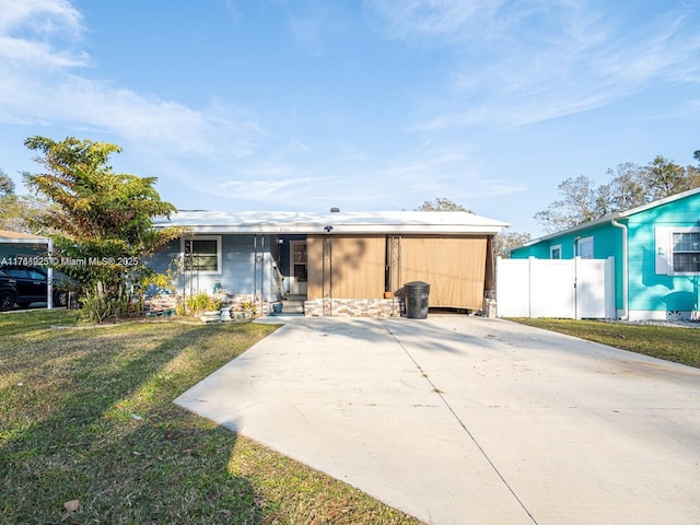 view of front facade featuring entry steps, a front yard, fence, and driveway