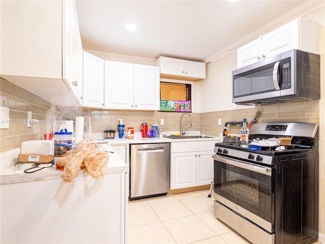 kitchen with light tile patterned flooring, a sink, stainless steel appliances, light countertops, and white cabinetry