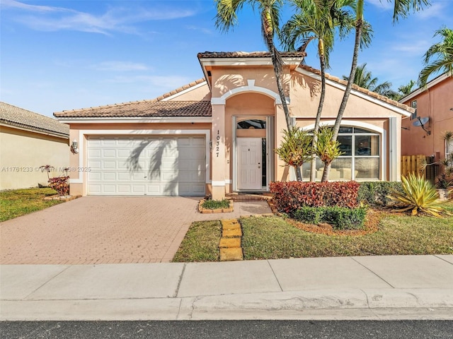 view of front facade with a tiled roof, decorative driveway, a garage, and stucco siding