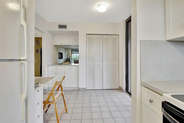 1001 Colony Point Cir Unit 514, Pembroke Pines, FL 33026 - kitchen featuring freestanding refrigerator, light countertops, white cabinets, a textured ceiling, and light tile patterned floors