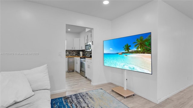 3349 W Park Rd, Hollywood, FL 33021 - interior space featuring appliances with stainless steel finishes, white cabinets, light wood finished floors, decorative backsplash, and baseboards