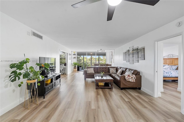 living area with visible vents, baseboards, light wood-type flooring, and ceiling fan