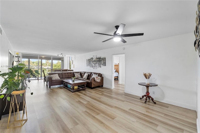 living area featuring floor to ceiling windows, baseboards, light wood finished floors, and ceiling fan