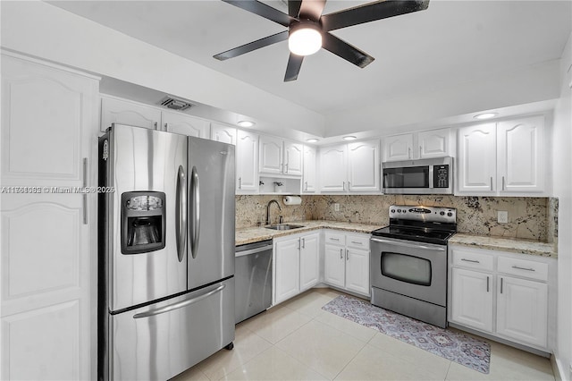 kitchen featuring light stone countertops, a sink, decorative backsplash, white cabinets, and appliances with stainless steel finishes