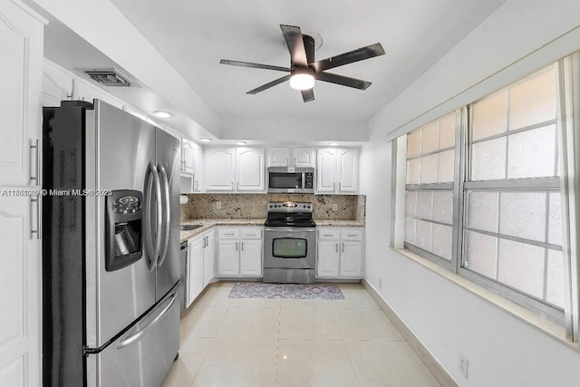 kitchen with light tile patterned flooring, decorative backsplash, appliances with stainless steel finishes, and white cabinetry