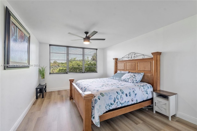 bedroom with ceiling fan, baseboards, and light wood-style floors