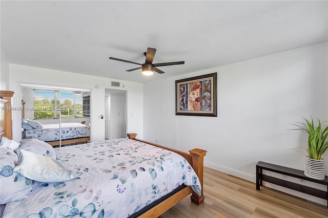 bedroom with ceiling fan, visible vents, baseboards, and wood finished floors