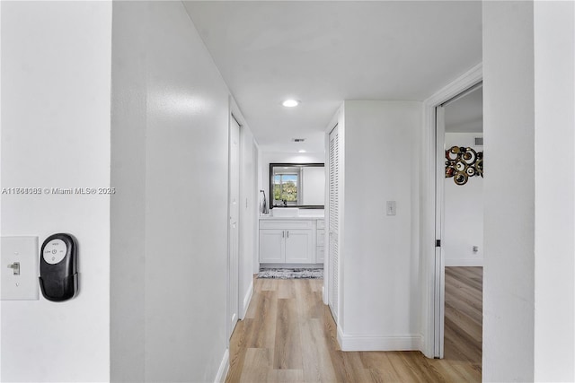 corridor featuring light wood-style flooring, recessed lighting, and baseboards