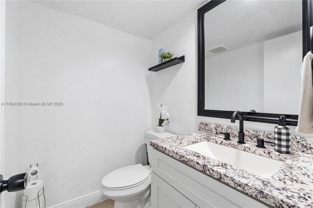 half bath with toilet, vanity, and baseboards