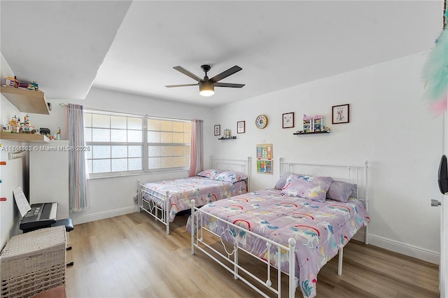 bedroom featuring a ceiling fan, baseboards, and wood finished floors