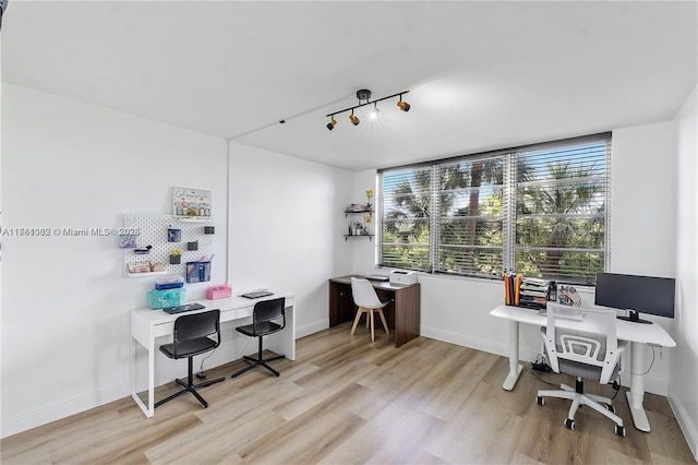 office area featuring baseboards, light wood-style flooring, and rail lighting