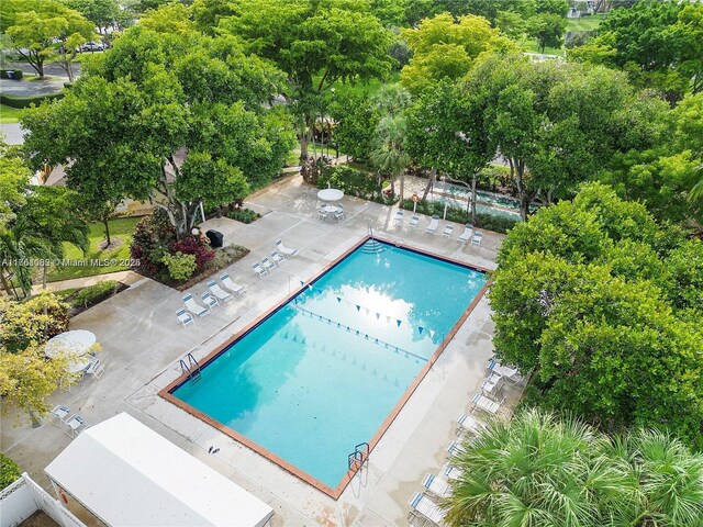 drone / aerial view of a nearby body of water, a golf course, and a tree filled landscape