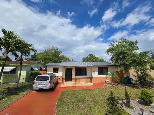 view of front of property with a standing seam roof, a front lawn, fence, and metal roof