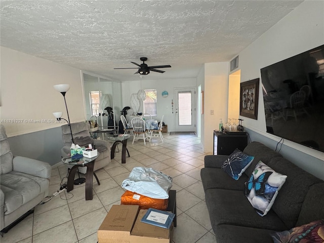 living room with tile patterned floors, visible vents, a textured ceiling, and ceiling fan