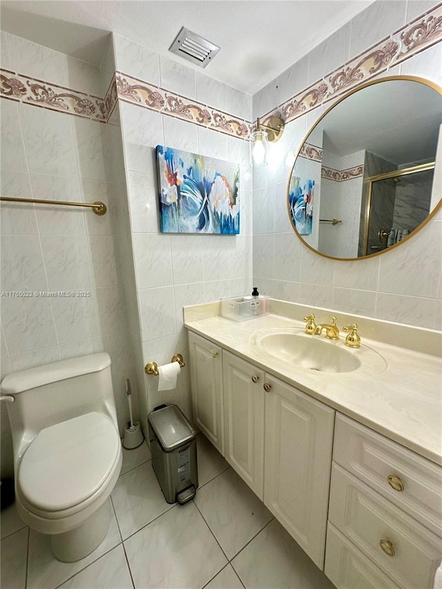 bathroom featuring visible vents, toilet, tile walls, a shower stall, and vanity