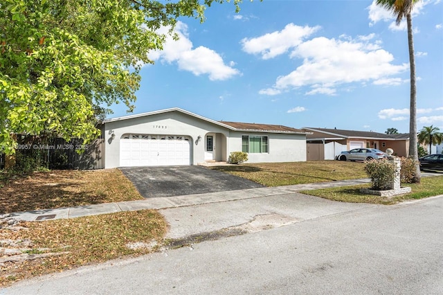 ranch-style home with stucco siding, driveway, a front yard, and a garage