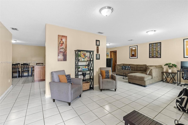 living room with light tile patterned flooring, baseboards, visible vents, and a textured ceiling