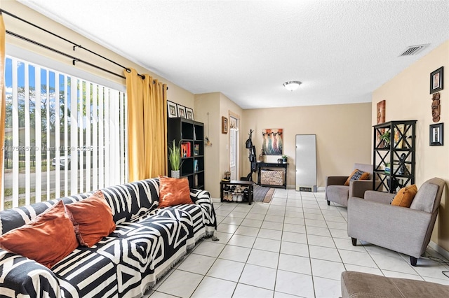 living area with light tile patterned floors, visible vents, and a textured ceiling