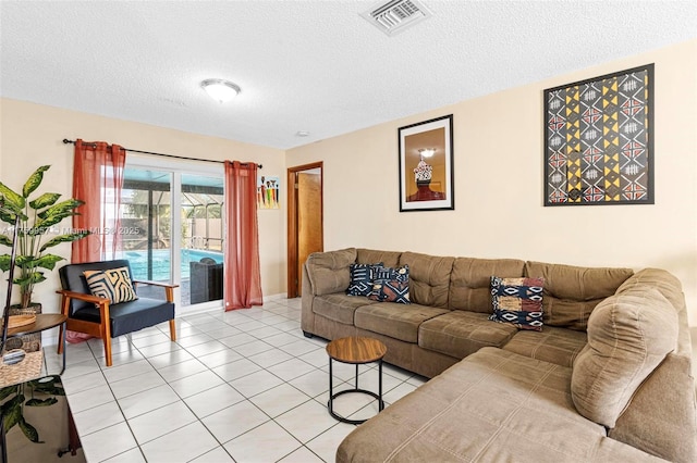 living room featuring light tile patterned floors, visible vents, and a textured ceiling