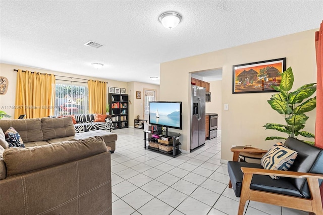 living area featuring light tile patterned floors, visible vents, and a textured ceiling