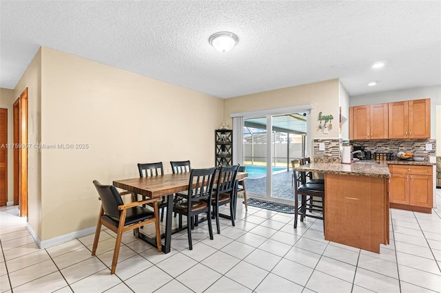 dining space with baseboards, a textured ceiling, and light tile patterned flooring