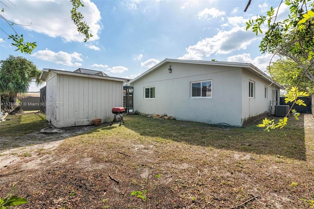 rear view of house with a lawn, a shed, fence, cooling unit, and an outdoor structure