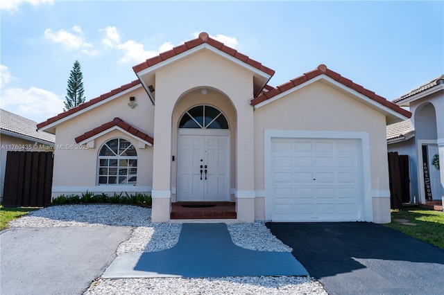 mediterranean / spanish house featuring stucco siding, a tile roof, and a garage