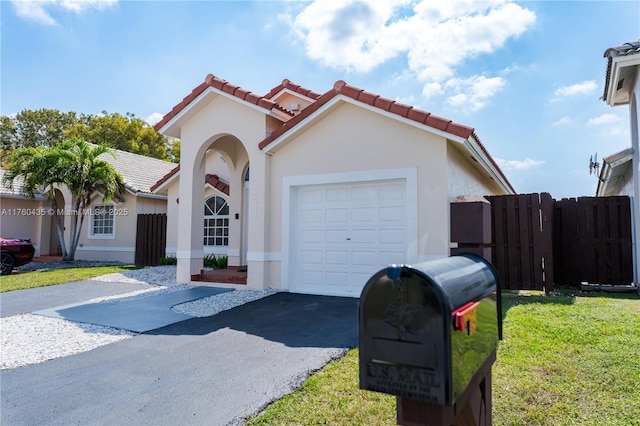 mediterranean / spanish-style home with fence, a tile roof, stucco siding, a garage, and driveway