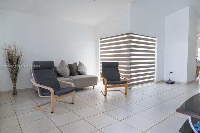 living area with lofted ceiling, baseboards, and tile patterned floors