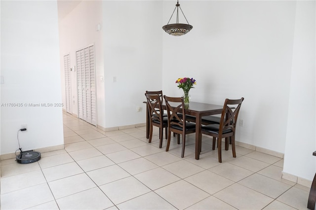 dining room featuring light tile patterned flooring, a high ceiling, and baseboards