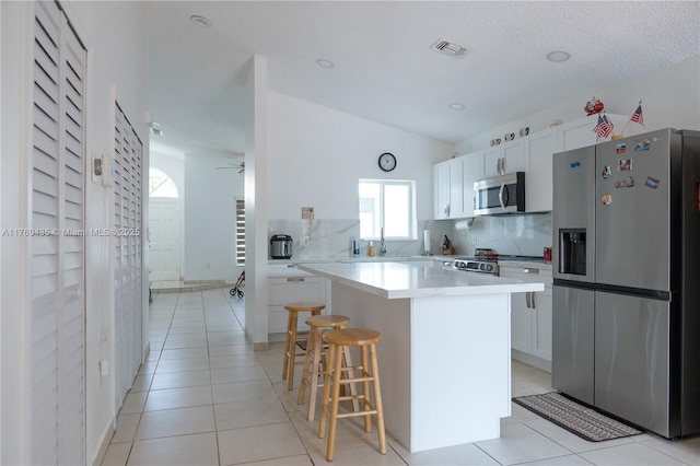 kitchen with light tile patterned floors, visible vents, a kitchen island, a breakfast bar, and appliances with stainless steel finishes