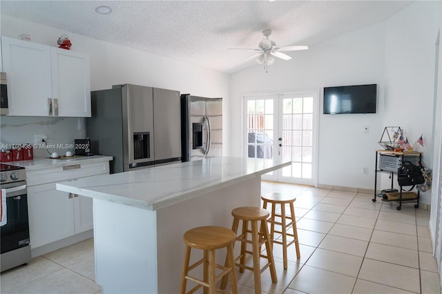 kitchen featuring lofted ceiling, a breakfast bar area, light tile patterned floors, and appliances with stainless steel finishes