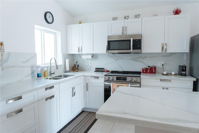 kitchen featuring tasteful backsplash, white cabinets, stainless steel appliances, and a sink