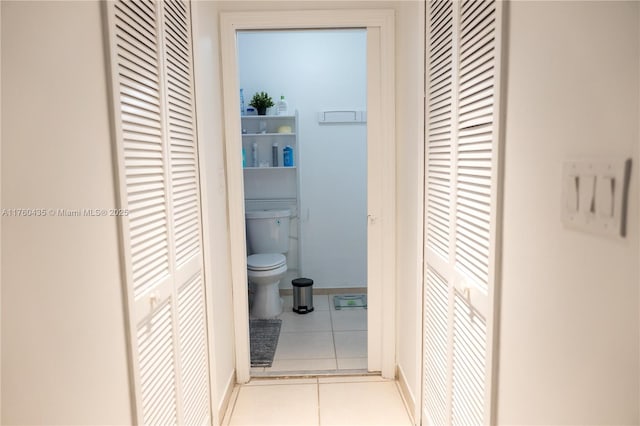 bathroom featuring a closet, baseboards, toilet, and tile patterned flooring